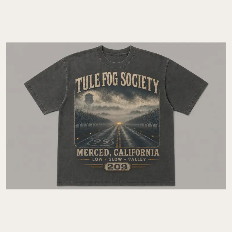 Washed charcoal Tule Fog Society Merced graphic T-shirt with headlights cutting through a foggy valley road